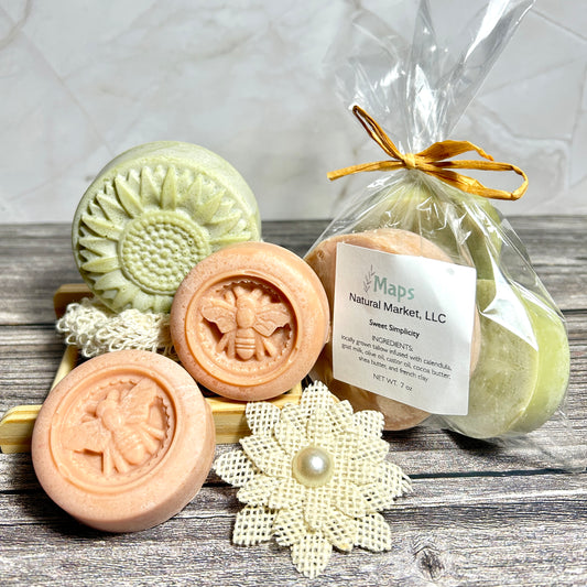 Handmade soaps with floral and bee designs on a wooden surface, goat milk and tallow unscented nut free, and baby friendly